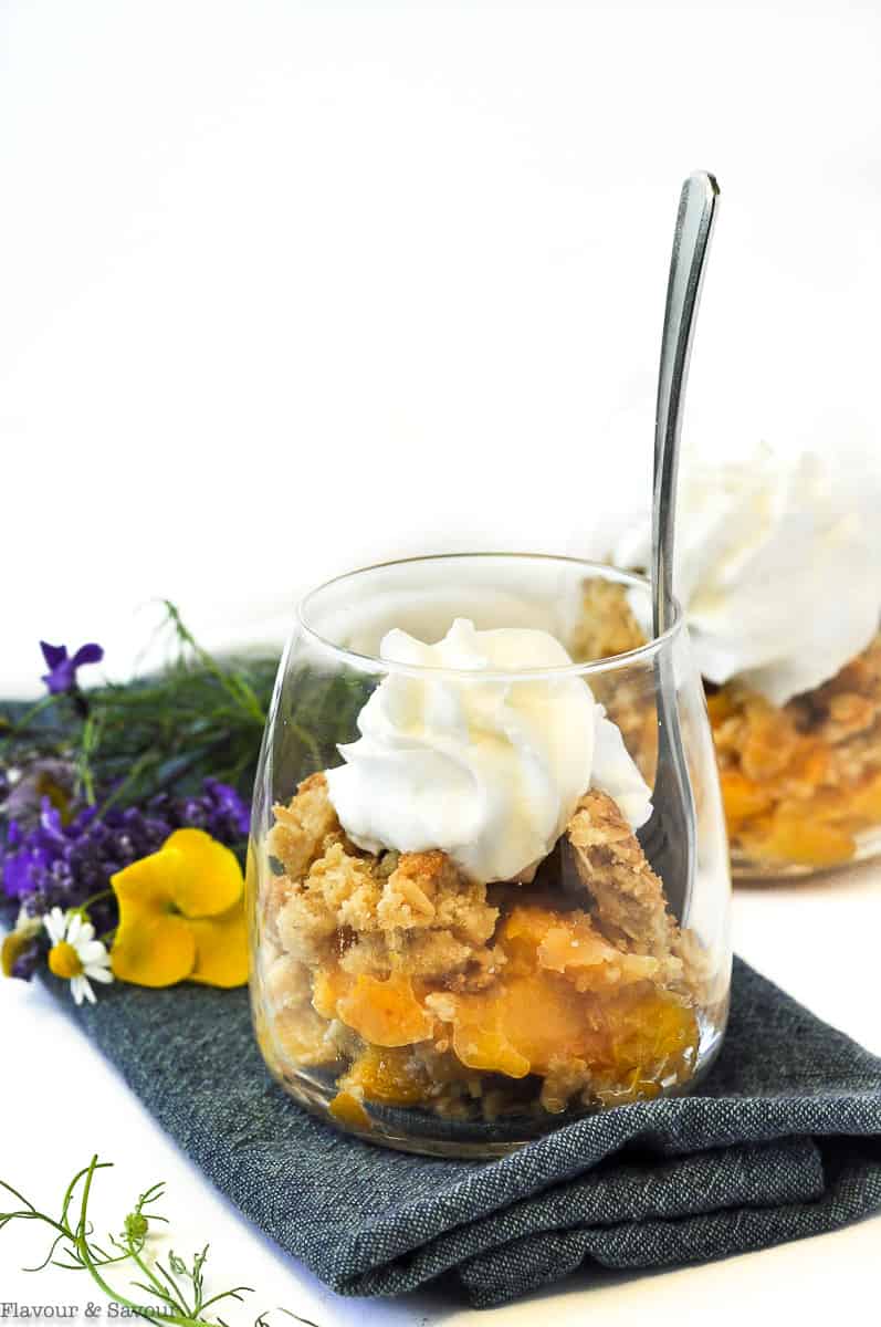 Peach Crisp with Bourbon and Vanilla in a dessert glass with a spoon