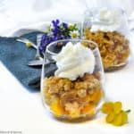 Two dessert glasses with Peach Crisp and whipped coconut milk