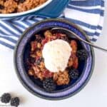 Overhead view of a bowl of apple blackberry crumble with ice cream.