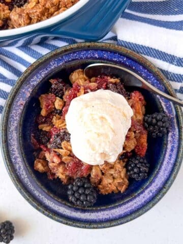 Overhead view of a bowl of apple blackberry crumble with ice cream.