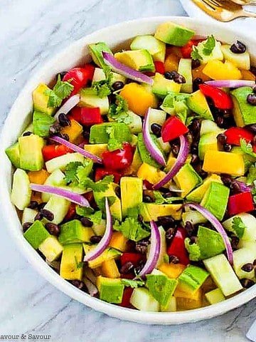 Overhead view of a round bowl with tomato avocado black bean salad.