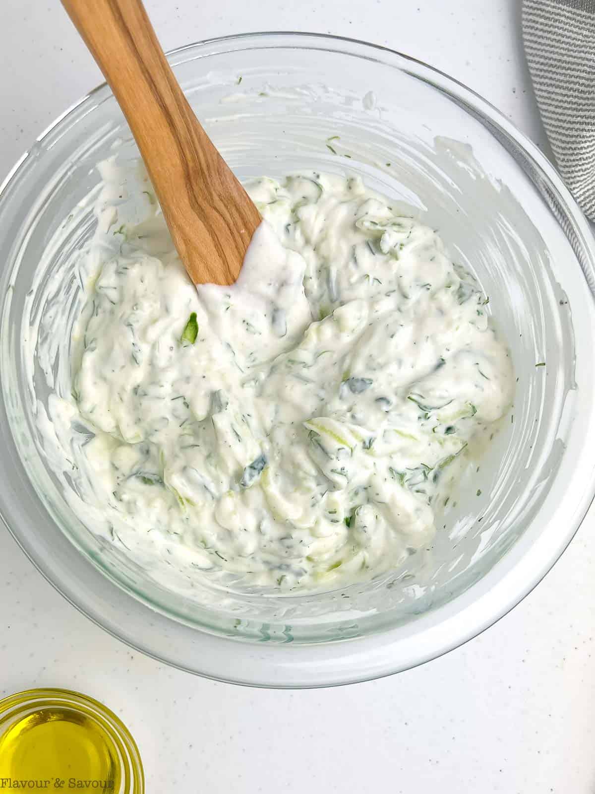 Preparing tzatziki sauce in a glass bowl.