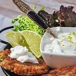 close up view of two salmon patties with lime yogurt dip
