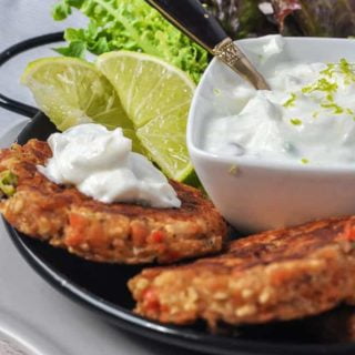close up view of two salmon patties with lime yogurt dip