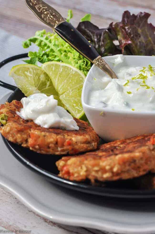 Close up view of two salmon patties with lime yogurt dip.