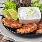 Baked salmon burgers with lime dip and lime slices.