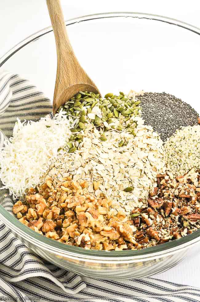 Ingredients for Pumpkin Spice Granola in a bowl with a wooden spoon