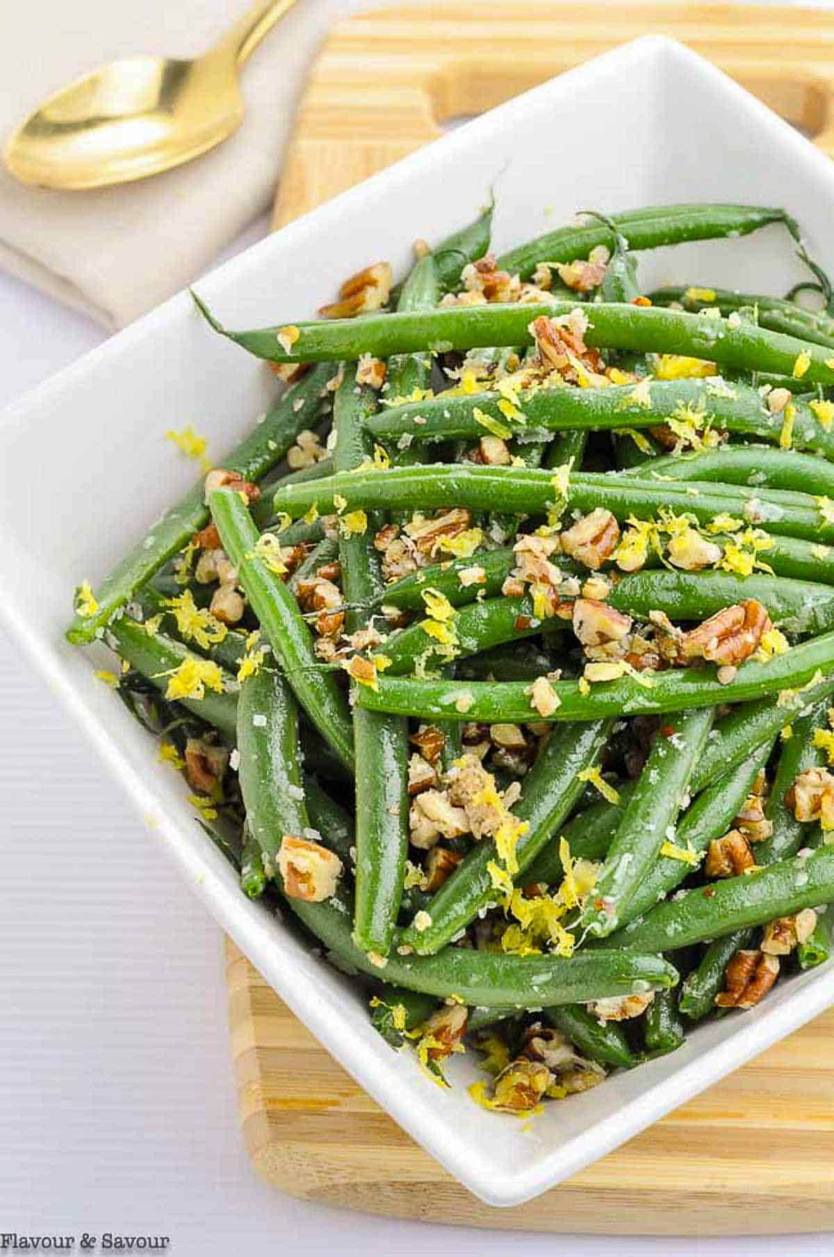 a bowl of green beans with parmesan cheese and pecans