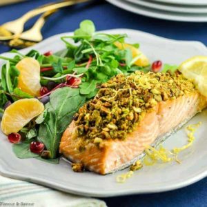 a pistachio-crusted fillet of salmon on a plate with a side salad