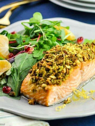 a pistachio-crusted fillet of salmon on a plate with a side salad