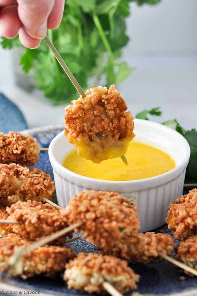 close up view of a skewered shrimp cake dunked in mango dip