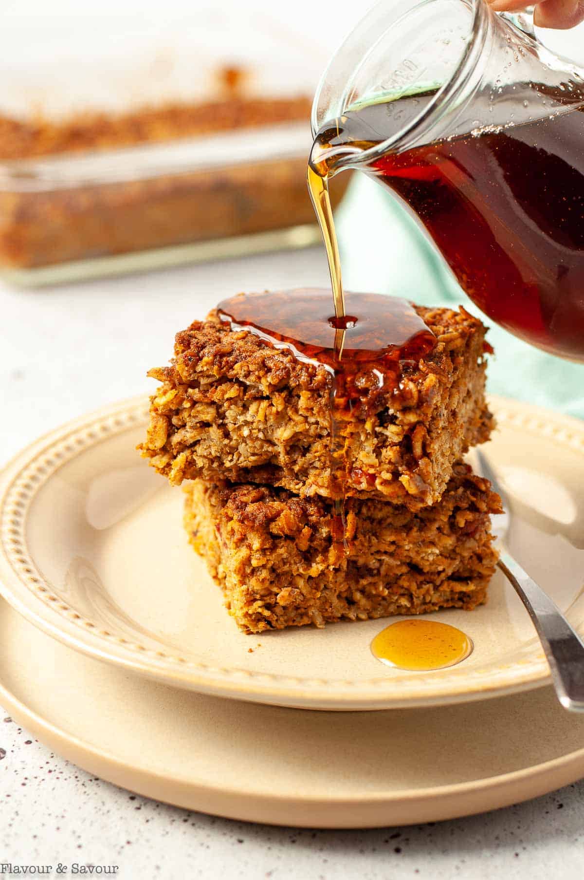 Two squares of pumpkin baked oatmeal with maple syrup