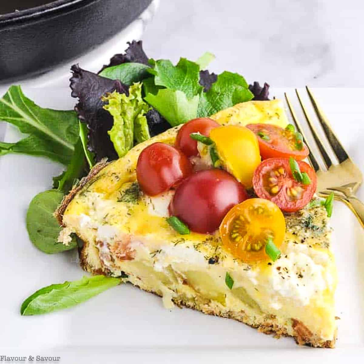 A wedge of smoked salmon spinach frittata garnished with cherry tomatoes.