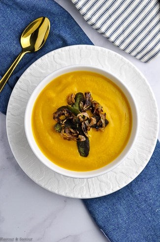 A bowl of butternut squash soup with toasted sage leaves and crispy shallots.