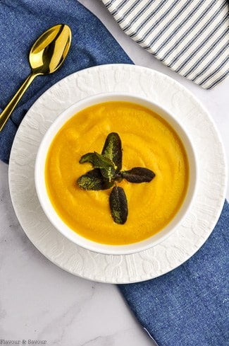 A bowl of butternut squash soup with toasted sage leaves.