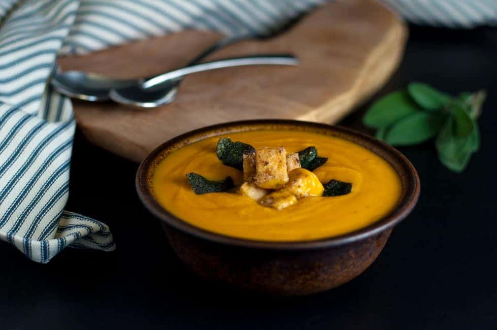 A bowl of soup with polenta croutons and sage leaf garnish.