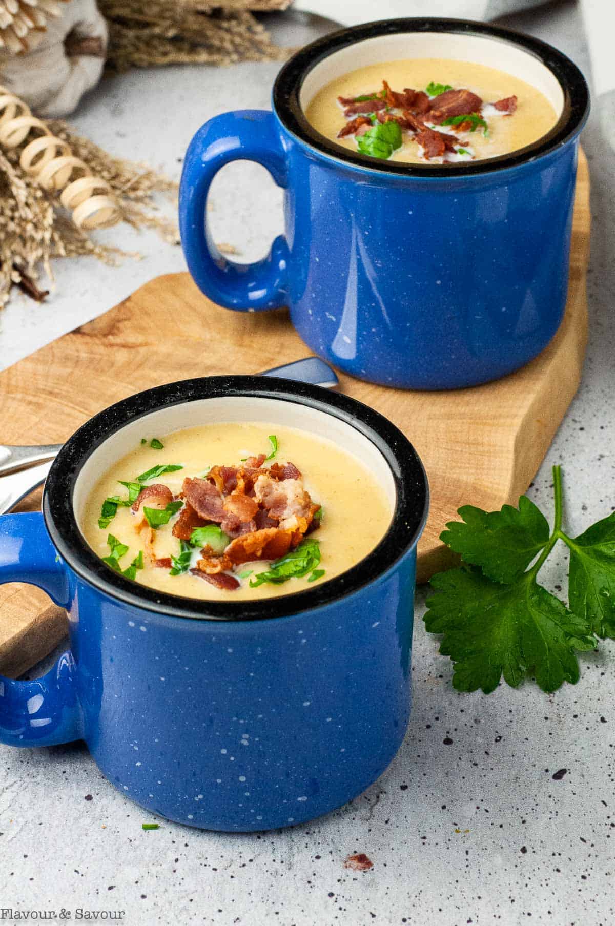 Two mugs of Instant Pot Potato Leek Soup on a board.