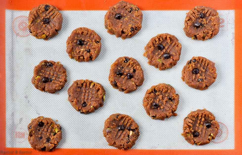 flattened cookies on a silicone baking sheet, ready to bake