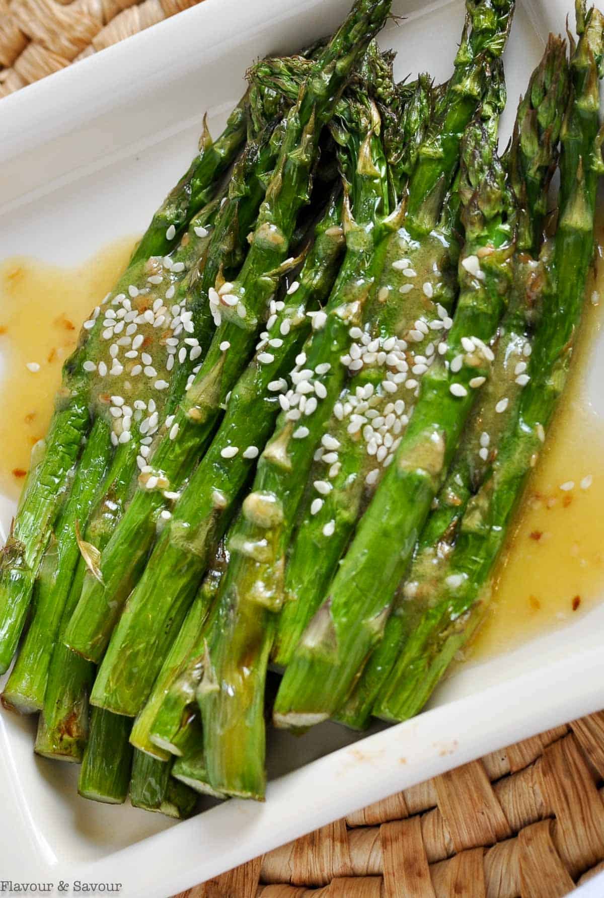 Air Fryer Asparagus drizzled with sesame miso dressing and white sesame seeds.