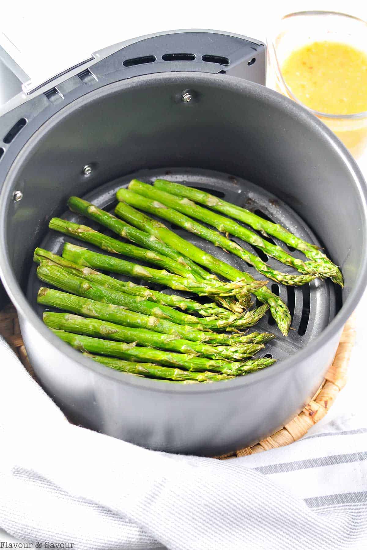 Asparagus stalks in and air fryer basket.