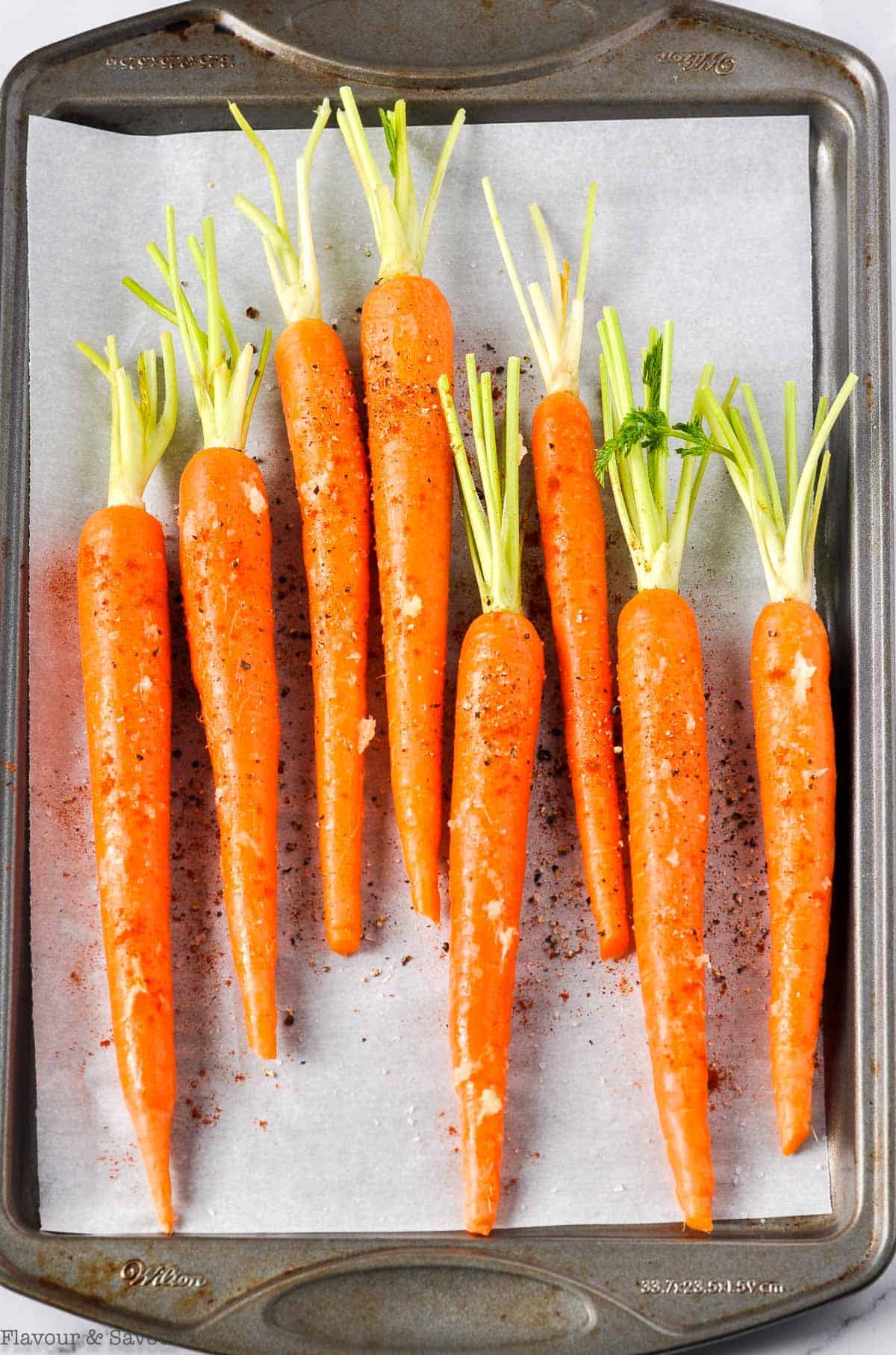 Whole carrots on a baking sheet ready to roast in the oven.