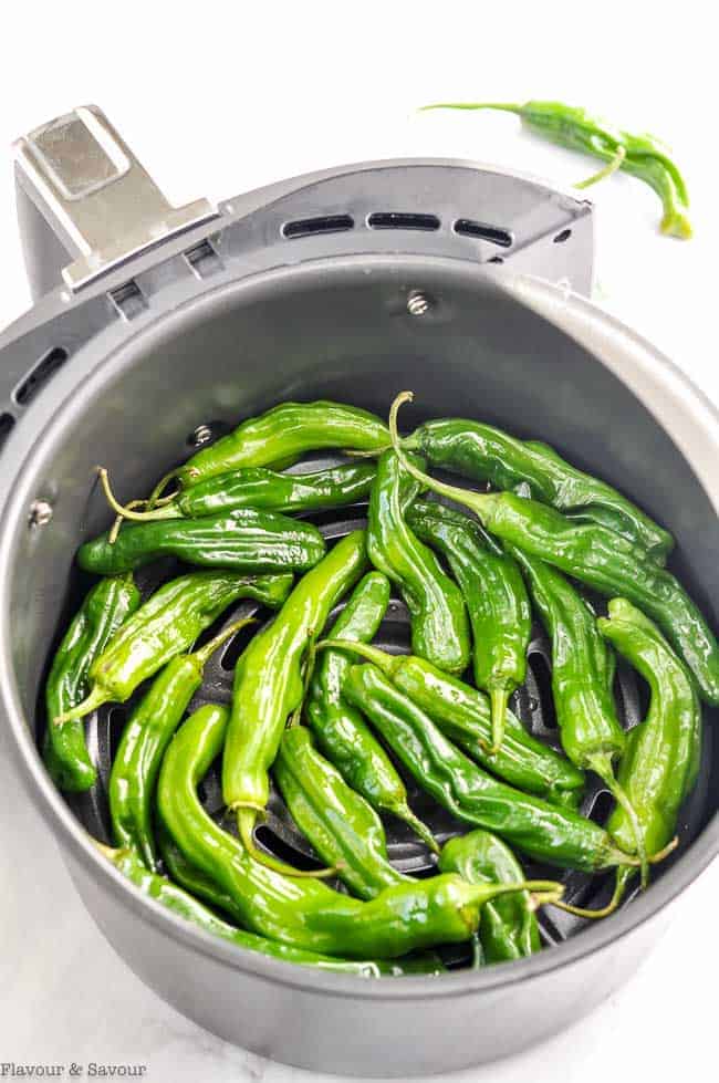 Raw Shishito Peppers (Padron Peppers) in an air fryer basket.