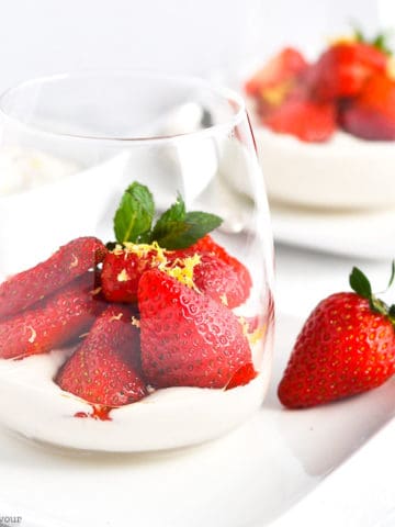 a dessert glass with cashew cream and macerated strawberries