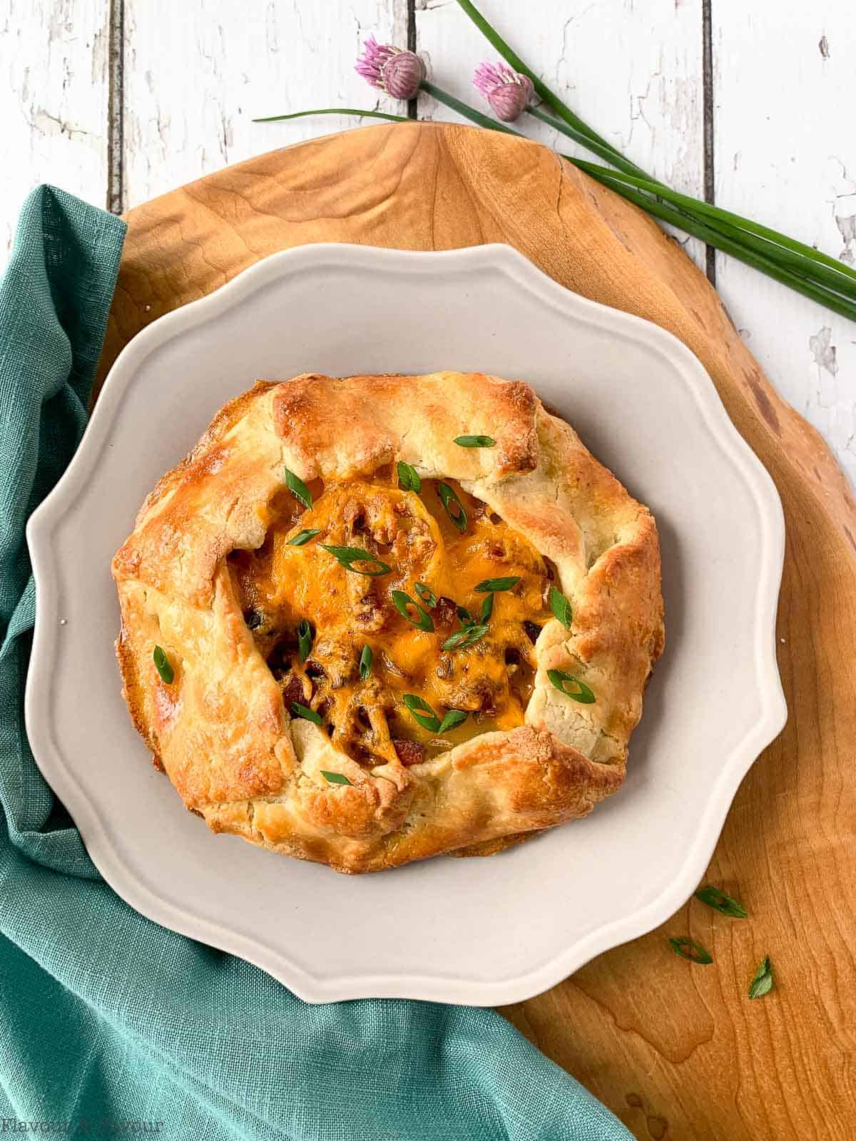 overhead view of a potato cheese and bacon galette  garnished with snipped green onions