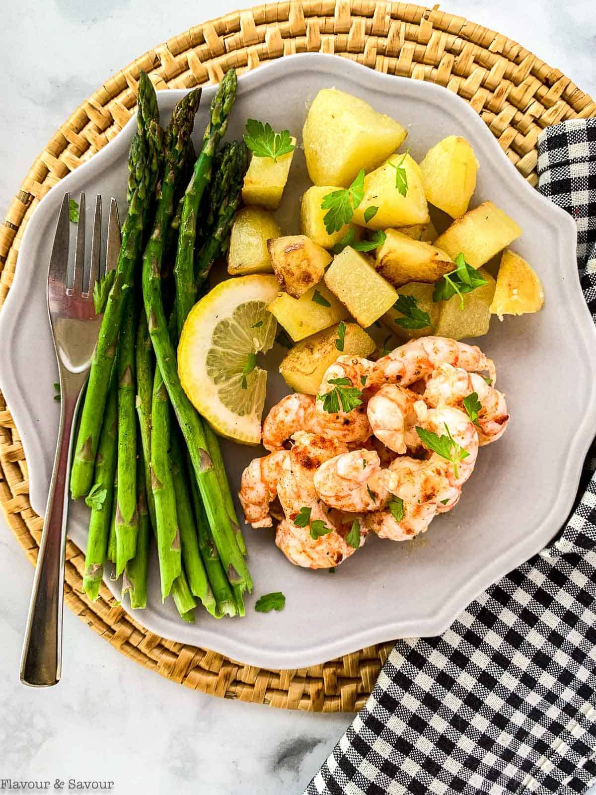 Sheet Pan Lemon Garlic Prawns with asparagus and roasted potatoes on a gray plate.