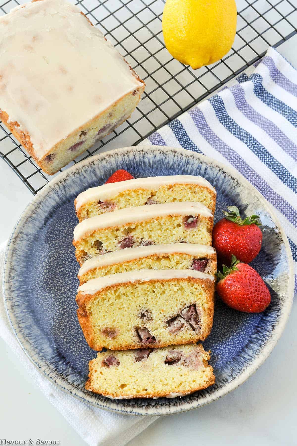 Overhead view of Strawberry Lemon Loaf on a rack with slices on a blue plate