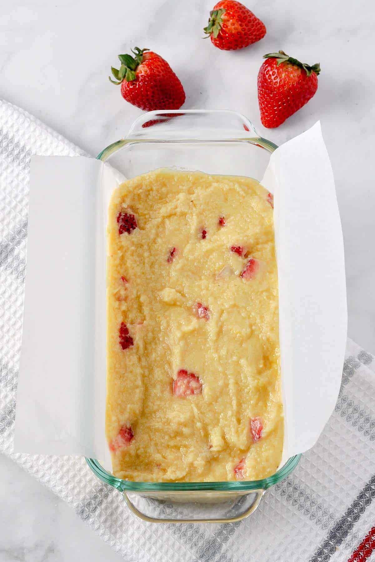 Spreading batter in a parchment paper lined loaf pan for Strawberry Lemon Loaf