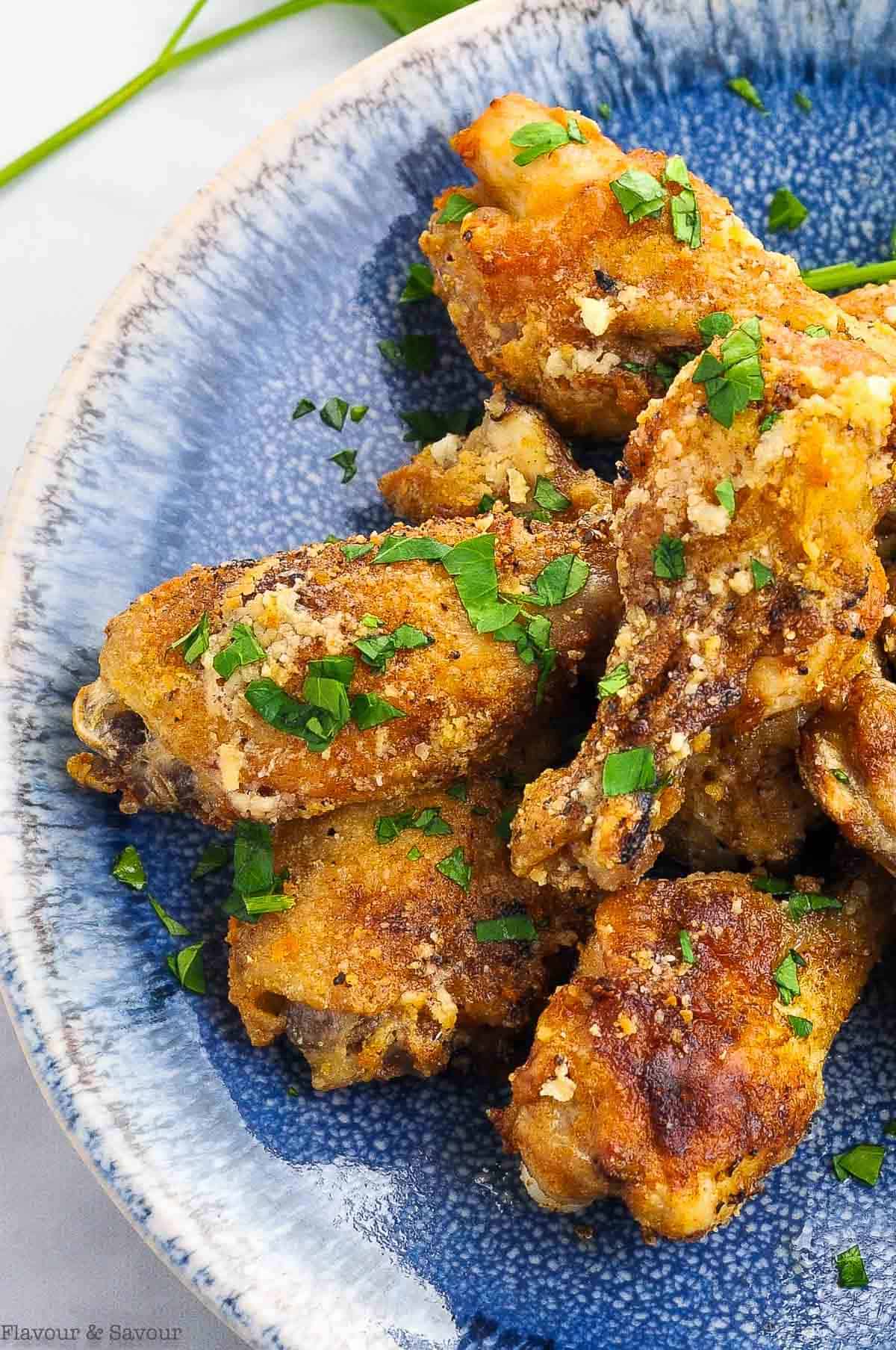 close up overhead view of garlic parmesan chicken wings on a blue plate
