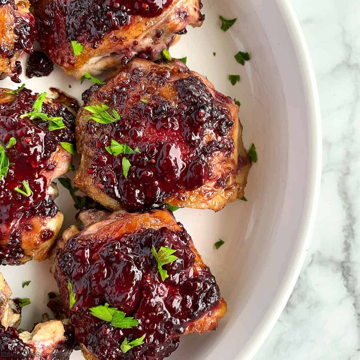 Close up view of Blackberry Glazed Chicken Thighs sprinkled with fresh parsley.