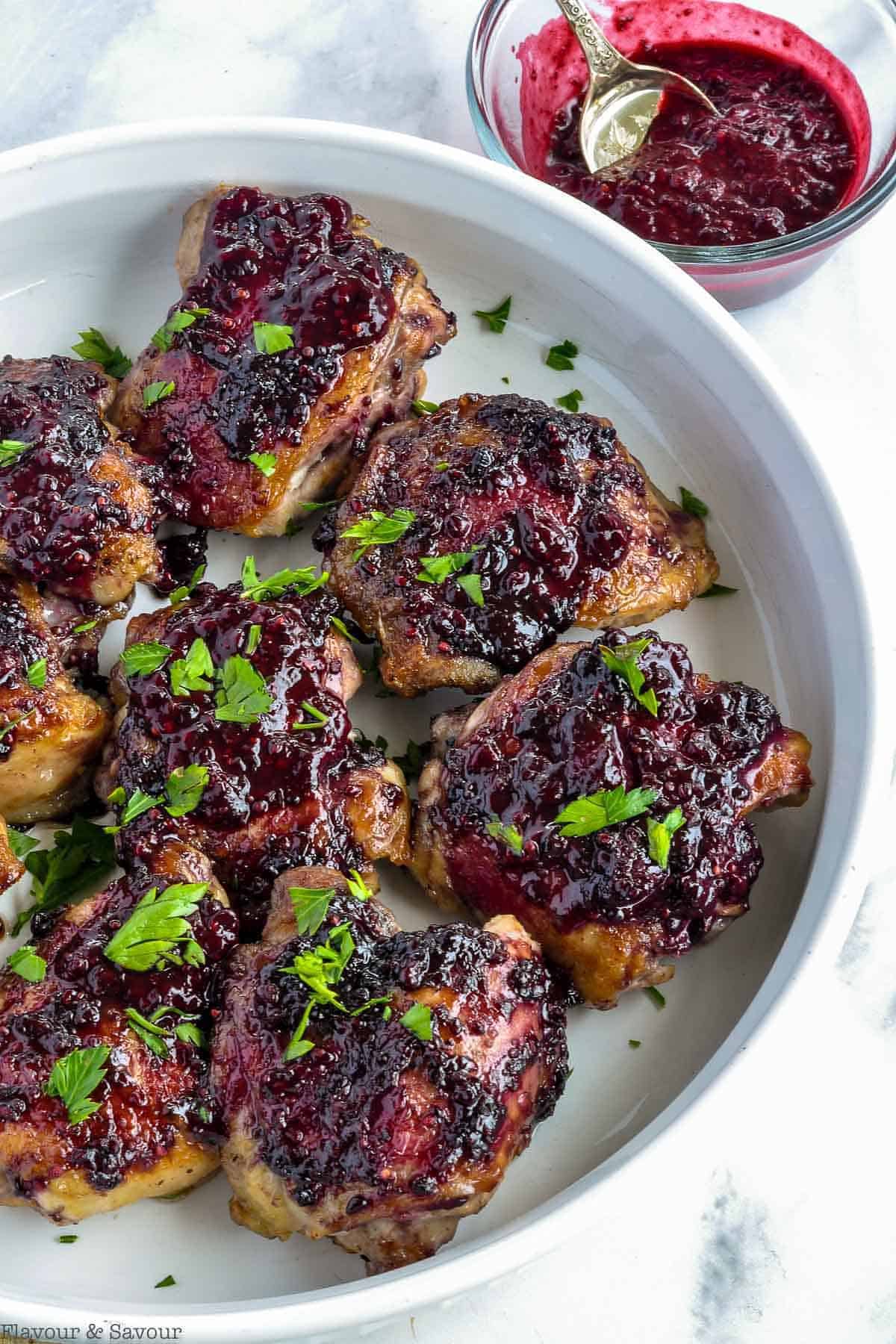 Overhead view of Blackberry Glazed Chicken thighs in a white serving dish