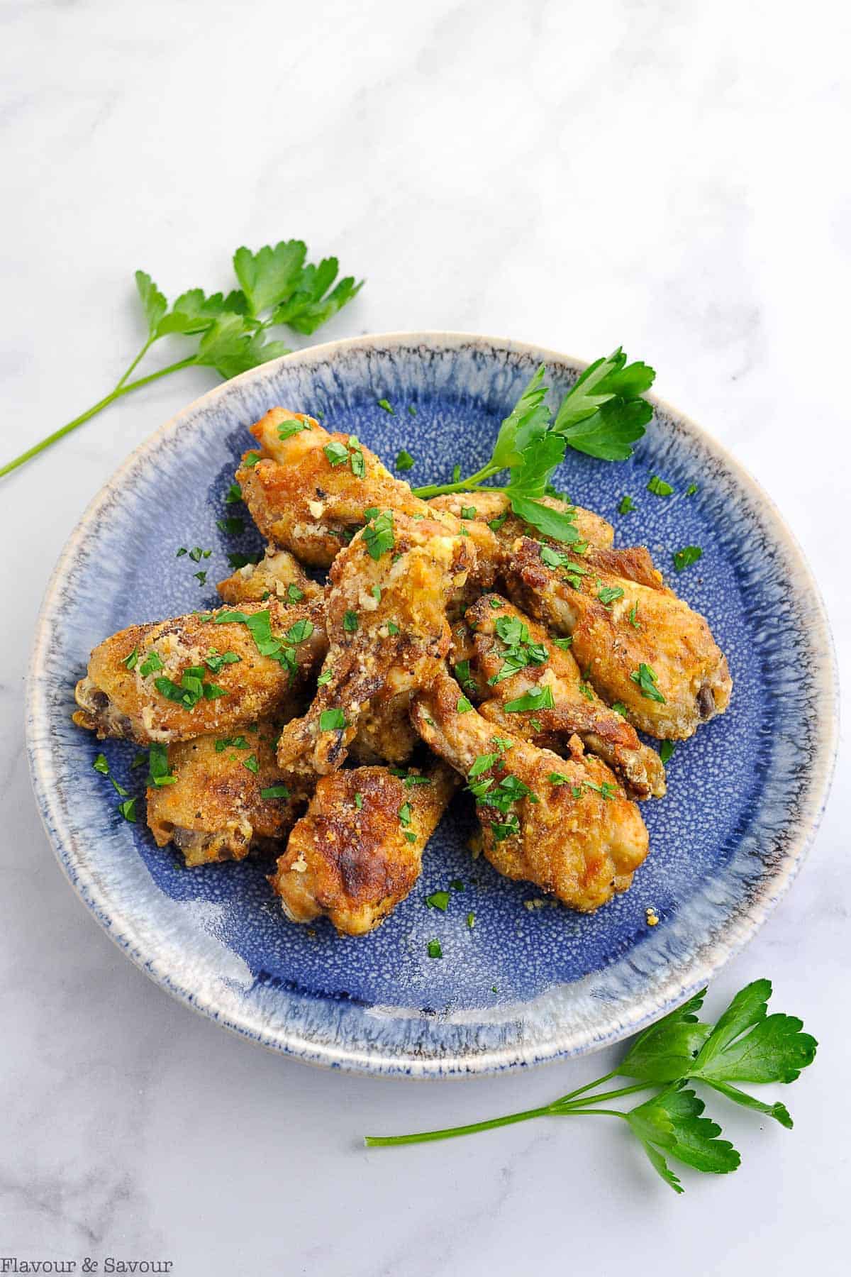 Air Fryer Garlic Parmesan Wings on a blue plate with fresh parsley