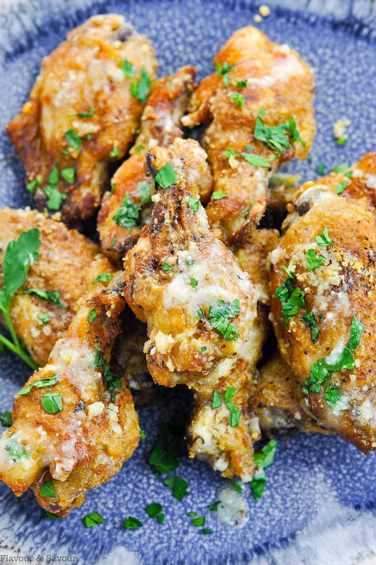 Garlic Parmesan Air Fryer Wings with fresh chopped parsley on a blue stoneware plate.