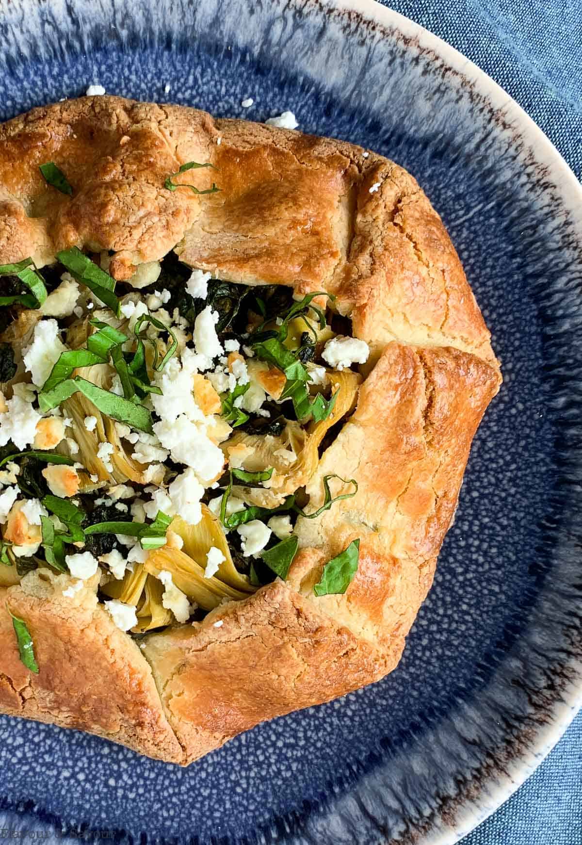 Overhead view of Spinach Artichoke Galette on a blue plate