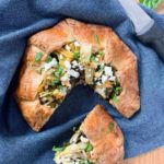 Gluten Free Spinach Artichoke Galette on a blue cloth with one wedge removed