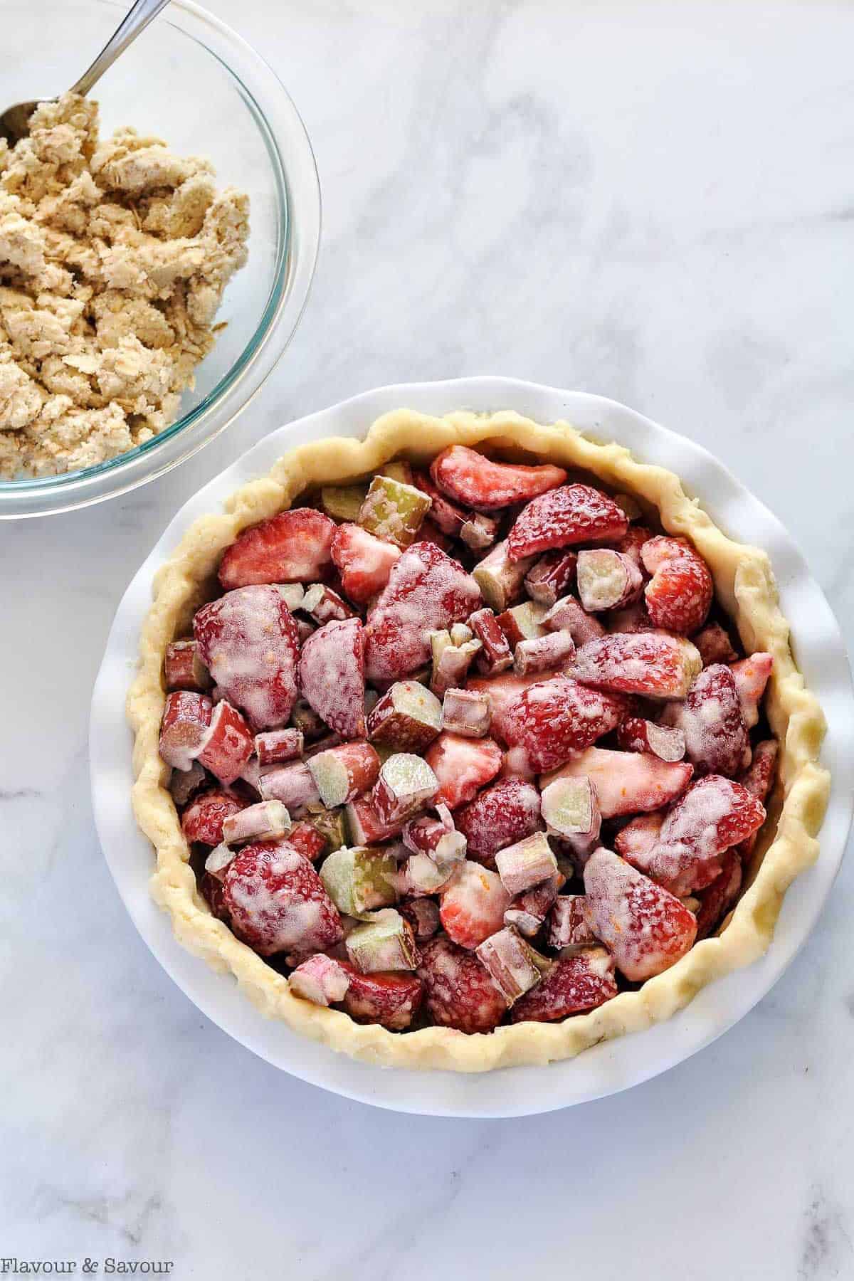 Preparing Strawberry Rhubarb Crumble Pie by filling the unbaked pie crust with sliced fruit.