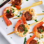 Overhead view of prawn chorizo skewers with lemon dip on the side