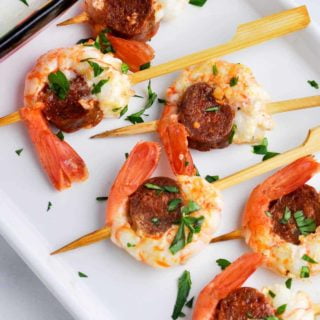 Overhead view of prawn chorizo skewers with lemon dip on the side