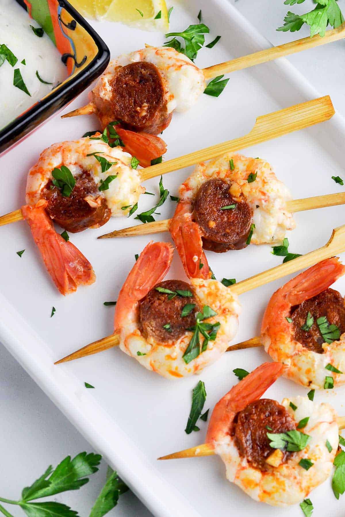 Overhead view of prawn chorizo skewers with lemon dip on the side