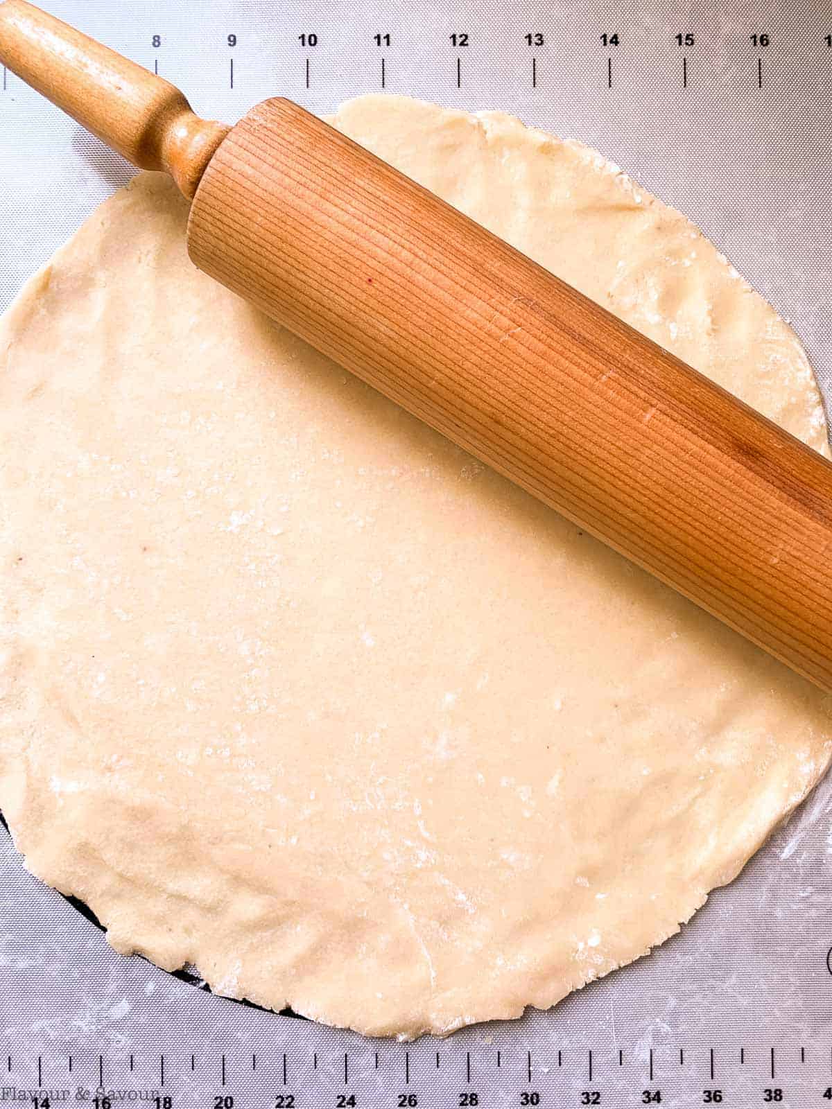 Rolling out pastry dough on a pastry mat.