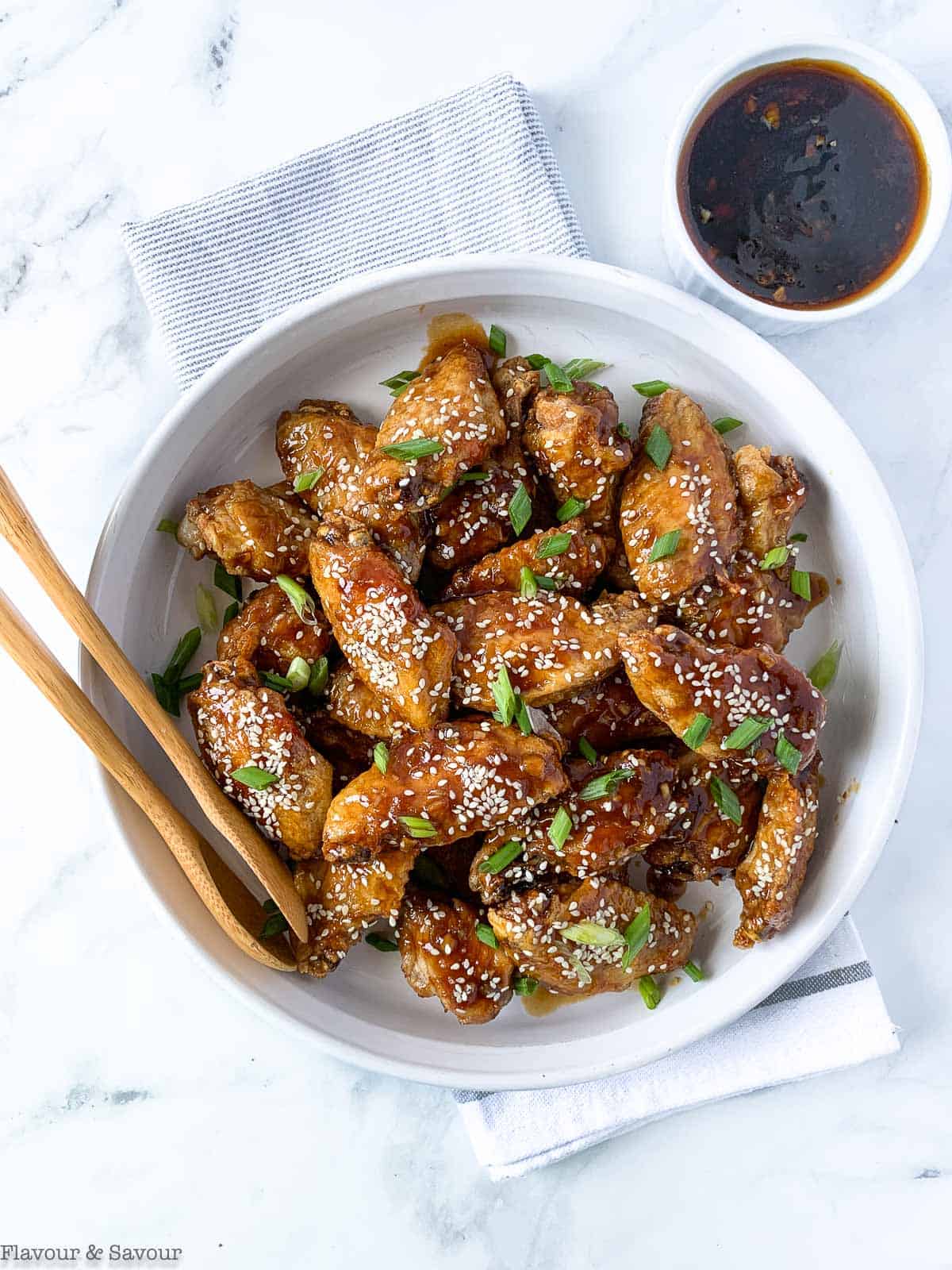 Air Fryer Teriyaki Chicken Wings in a white round dish with tongs