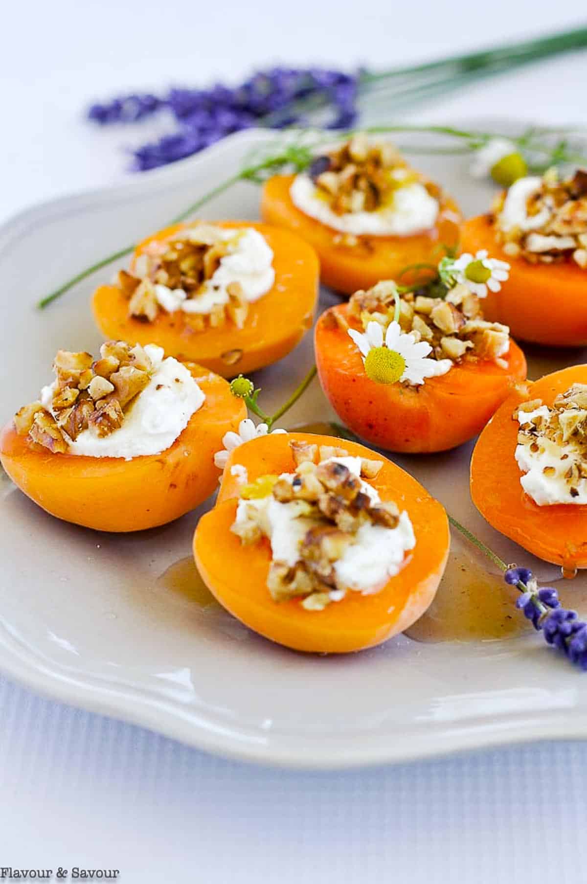 A plate with several fresh apricots topped with goat cheese and lavender honey.