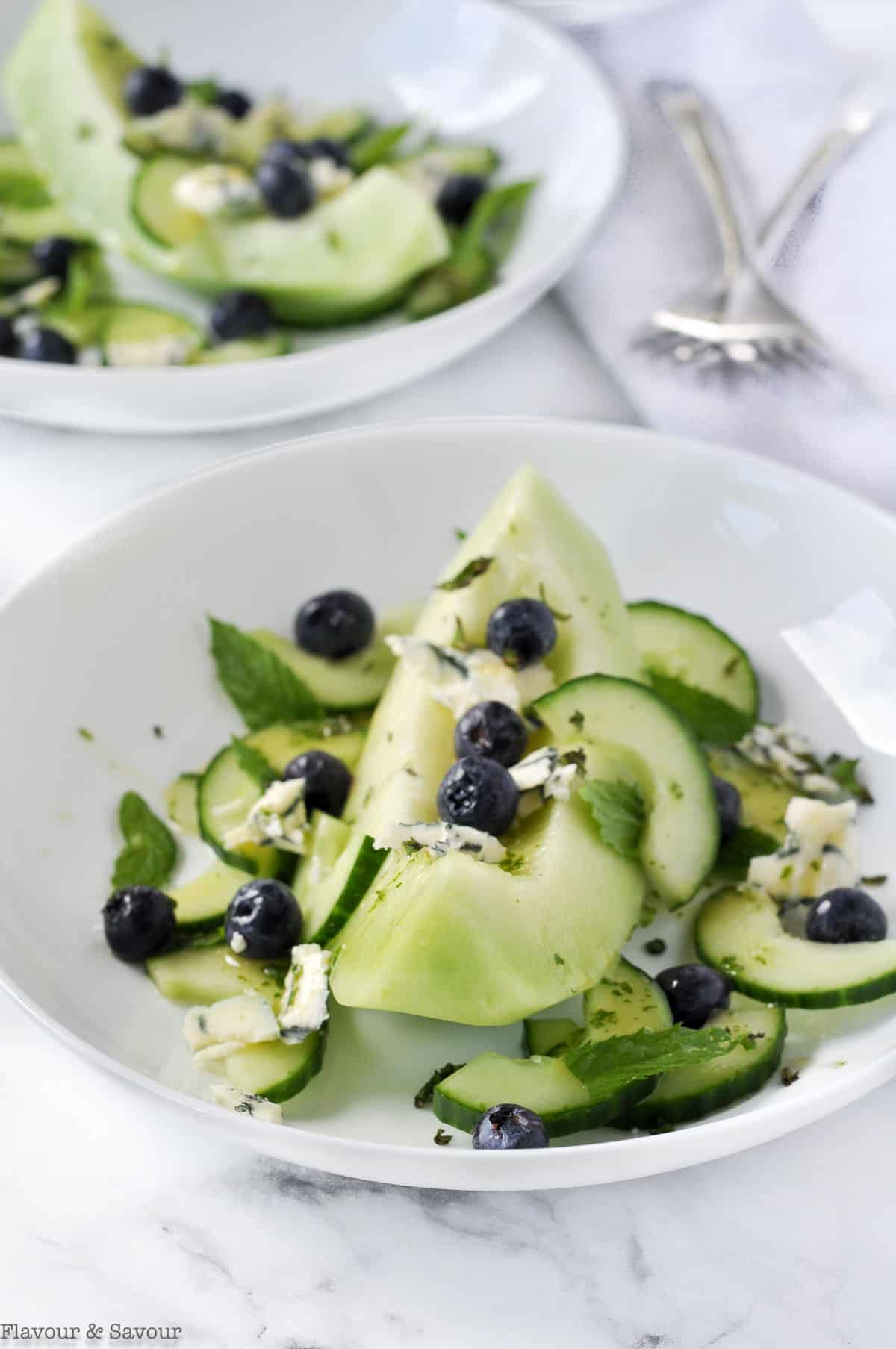 A close up view of Honeydew Melon Salad with blueberries, blue cheese and mint leaves