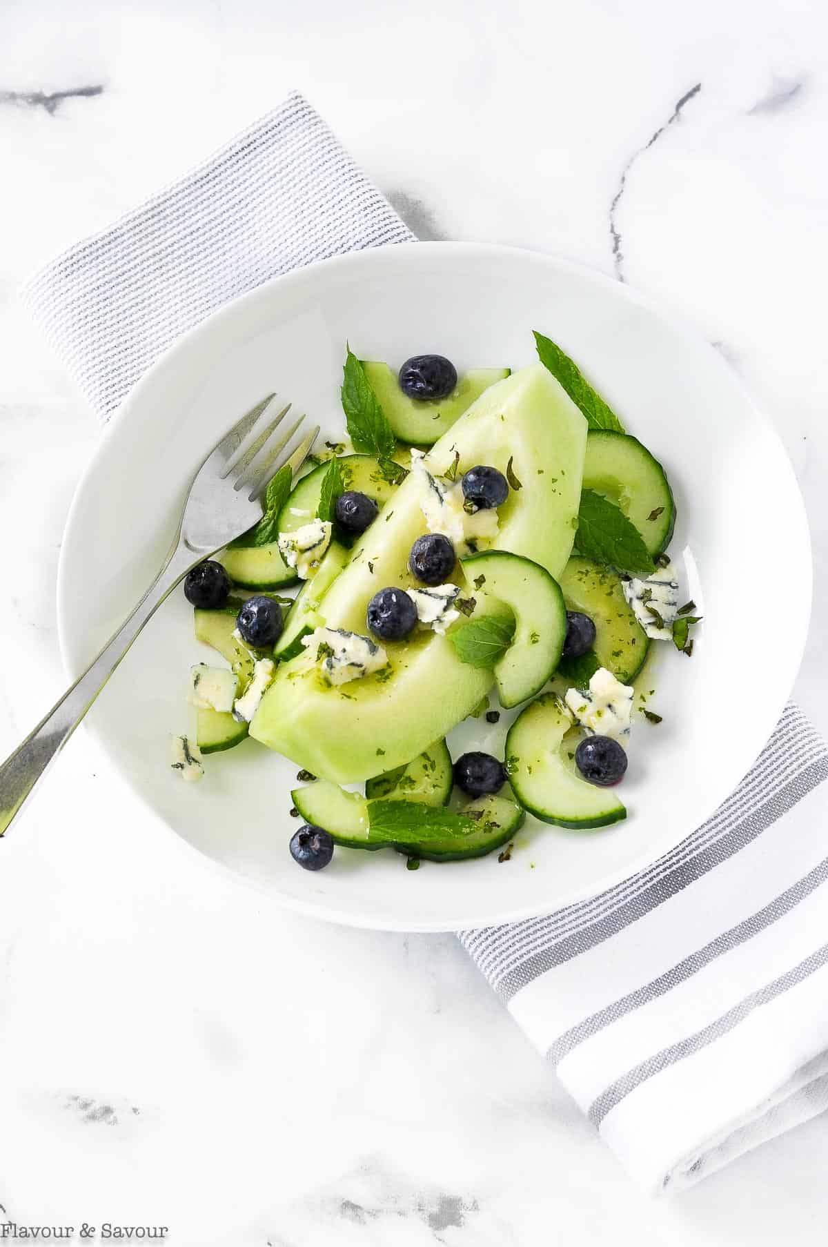 a single bowl of Honeydew Melon Salad in a white bowl with a fork