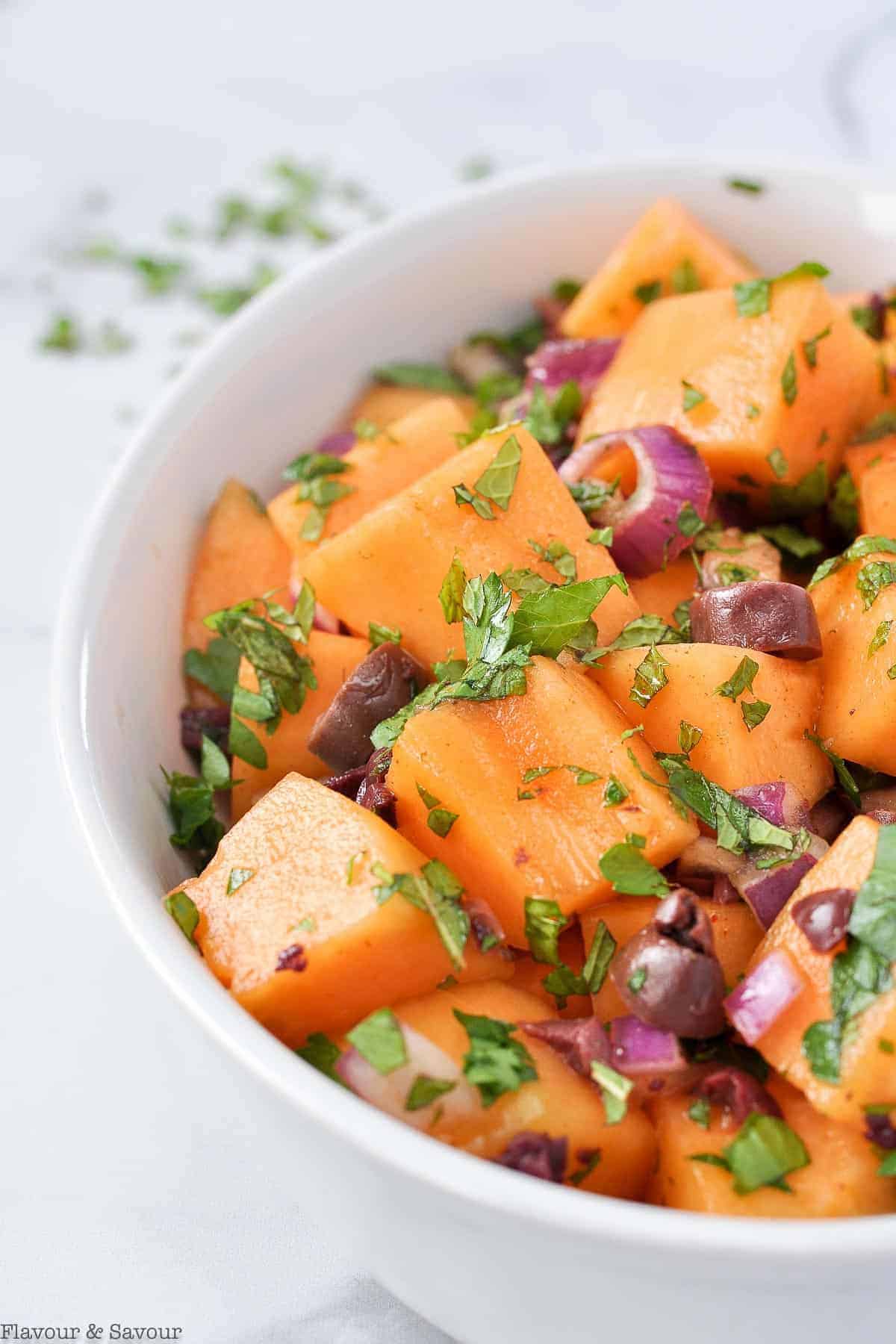 Close up view of Mediterranean Cantaloupe Salad with red onion, parsley and mint