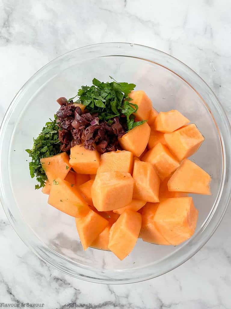 add cantaloupe, herbs and olives to a bowl