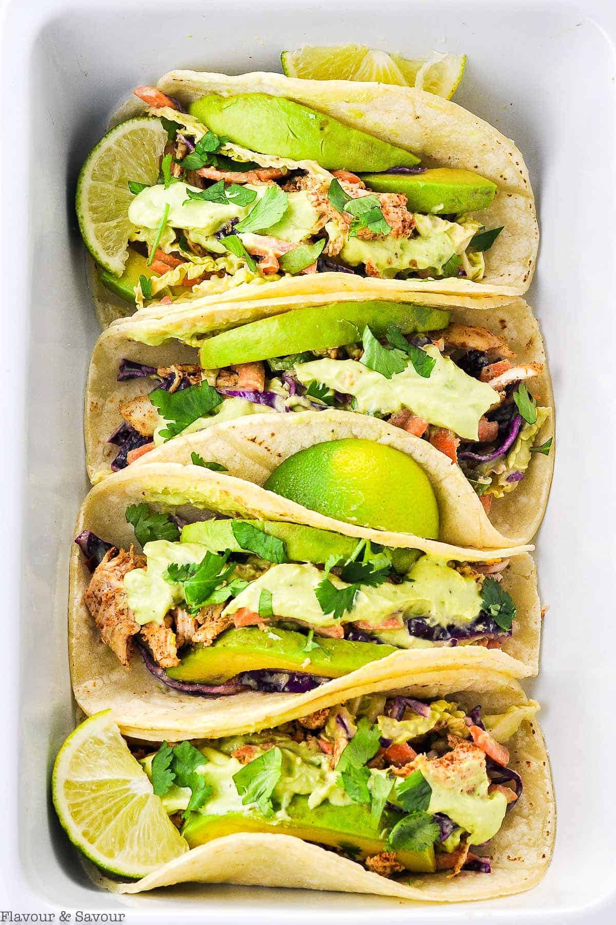 Four Shredded Chicken Tacos in a white serving dish